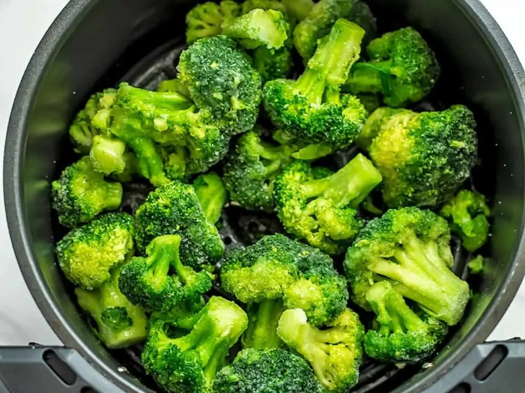 Frozen broccoli in the air fryer before cooking.
