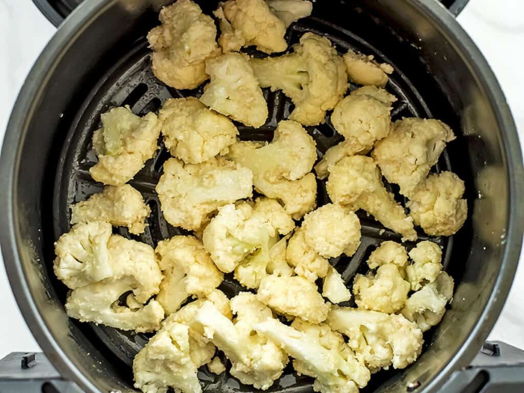 Breaded cauliflower in an air fryer basket.