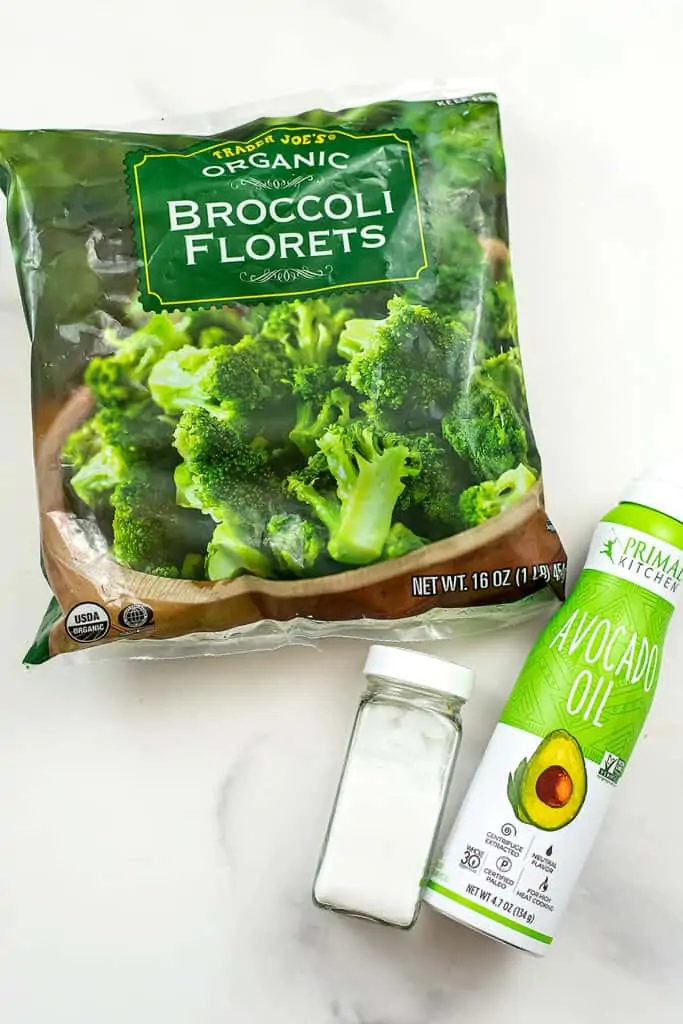Ingredients for air fryer frozen broccoli on a white table. 