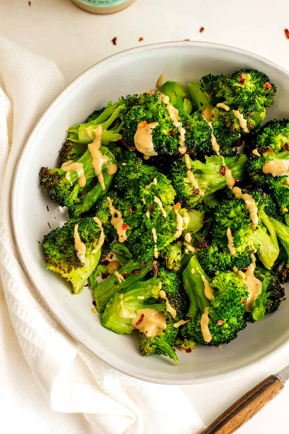 Air fryer frozen broccoli cooked with tahini drizzled over top.