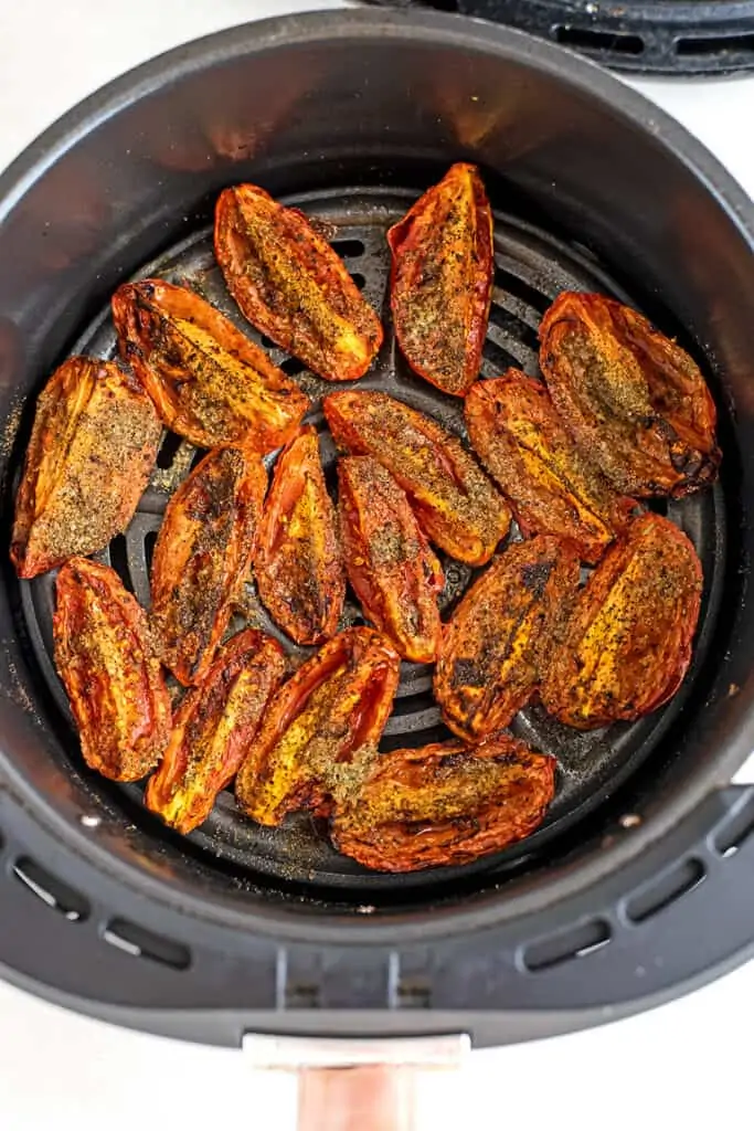 Roma tomatoes in the air fryer basket after roasting.