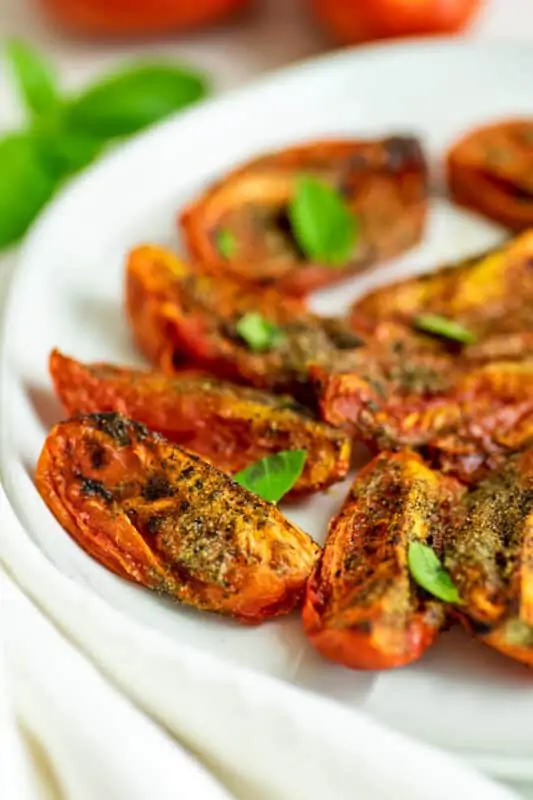 Quartered roma tomatoes after cooking in the air fryer on plate.