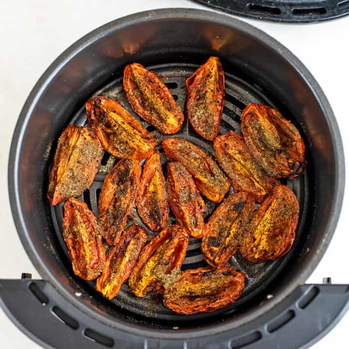 Roasted roma tomatoes in the air fryer basket.