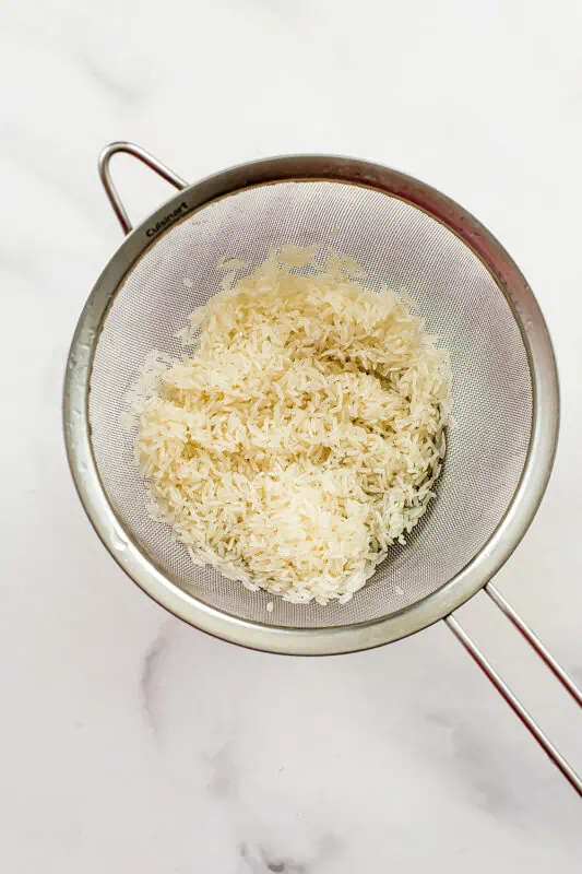 Jasmine rice in a mesh strainer.