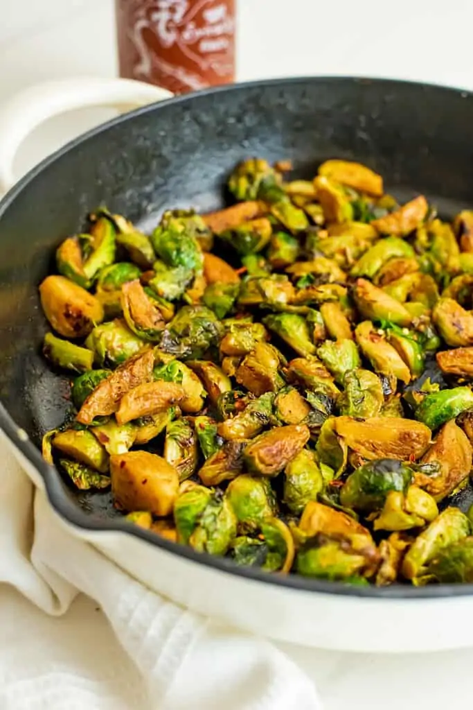 Cast iron skillet filled with cooked bang bang brussel sprouts.