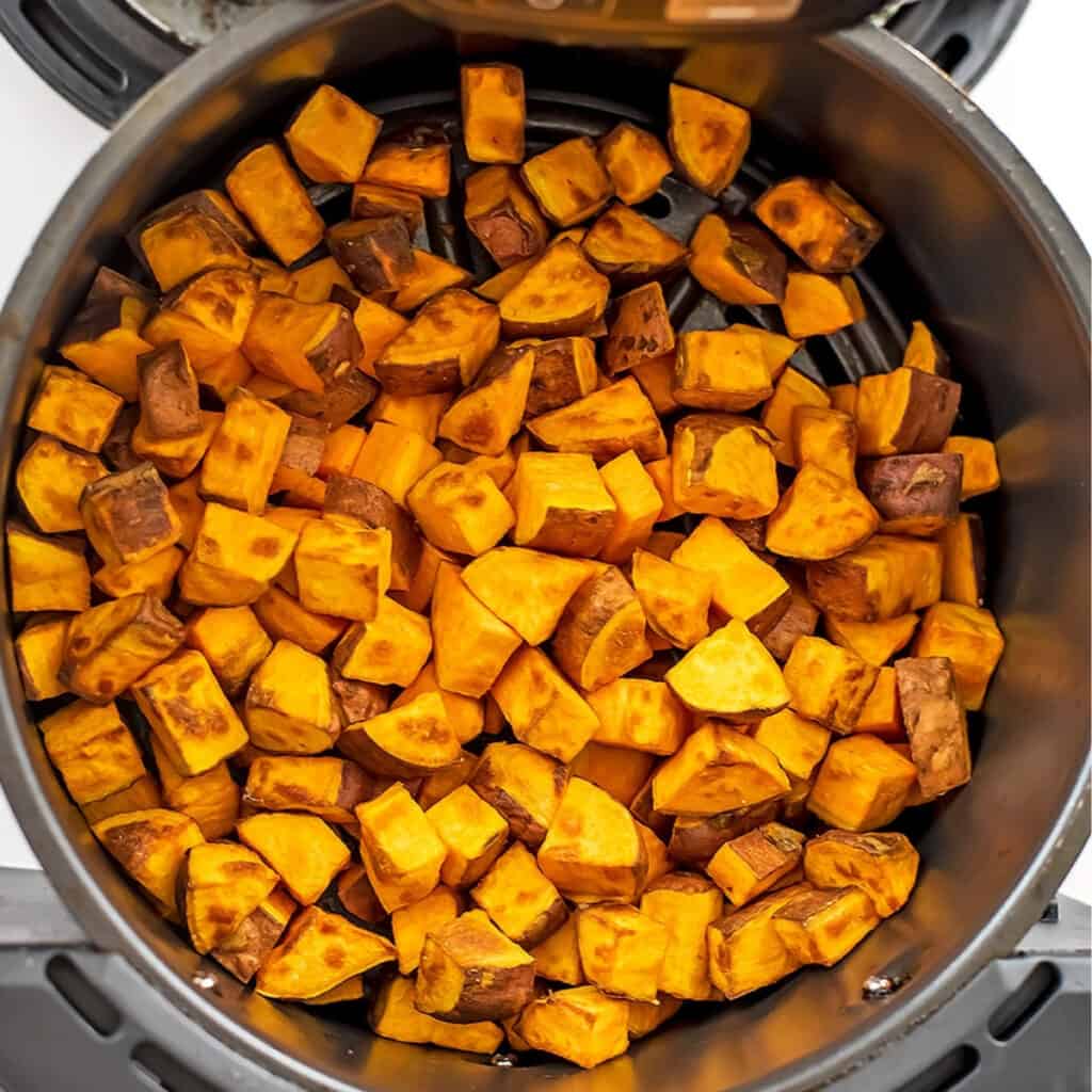 Sweet potato cubes in air fryer basket after cooking.