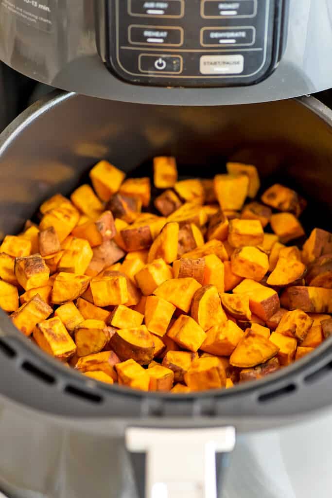 Air fryer filled with sweet potato cubes after cooking.