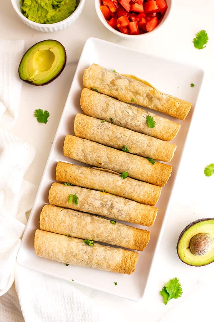 Air fryer taquitos on a white serving dish.