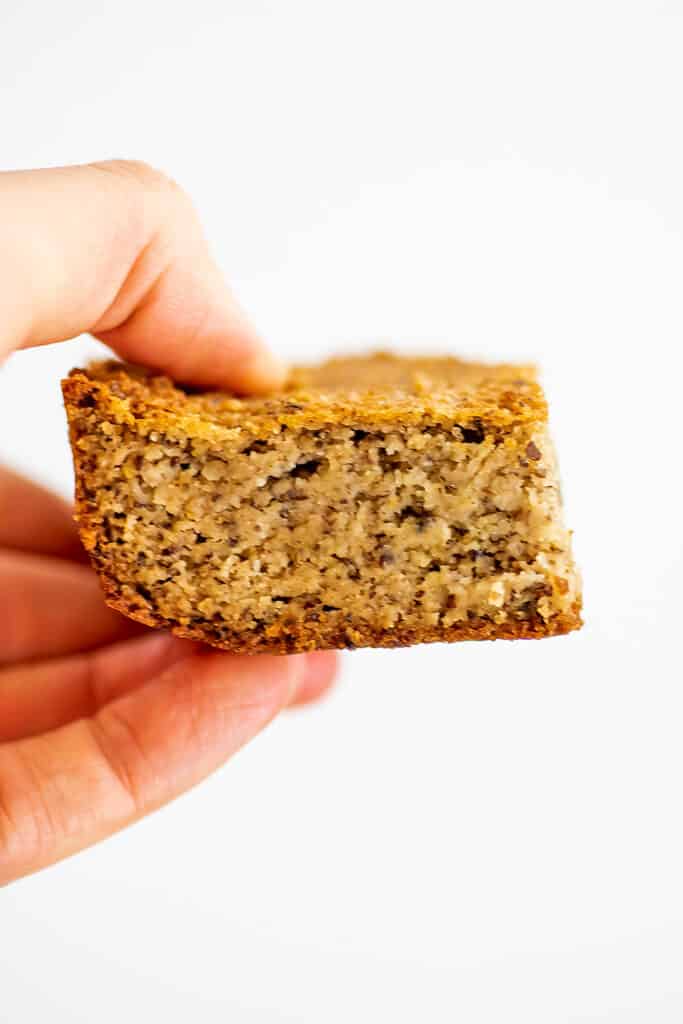 Hand holding a single slice of almond flour corn bread.