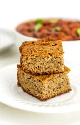 Two slices of almond flour corn bread stacked on a plate.