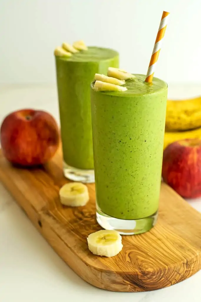 Two glasses full of spinach apple banana smoothies.