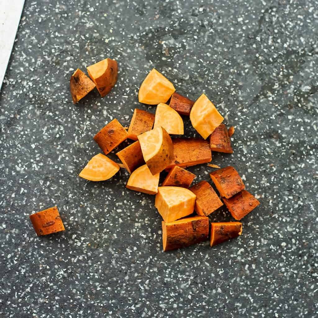 Sweet potatoes being chopped into 1/2 inch cubes for the hash.