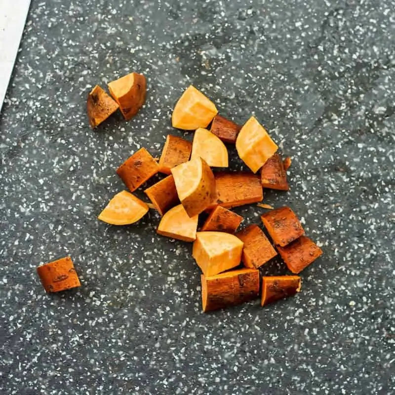 Sweet potatoes being chopped into 1/2 inch cubes for the hash.
