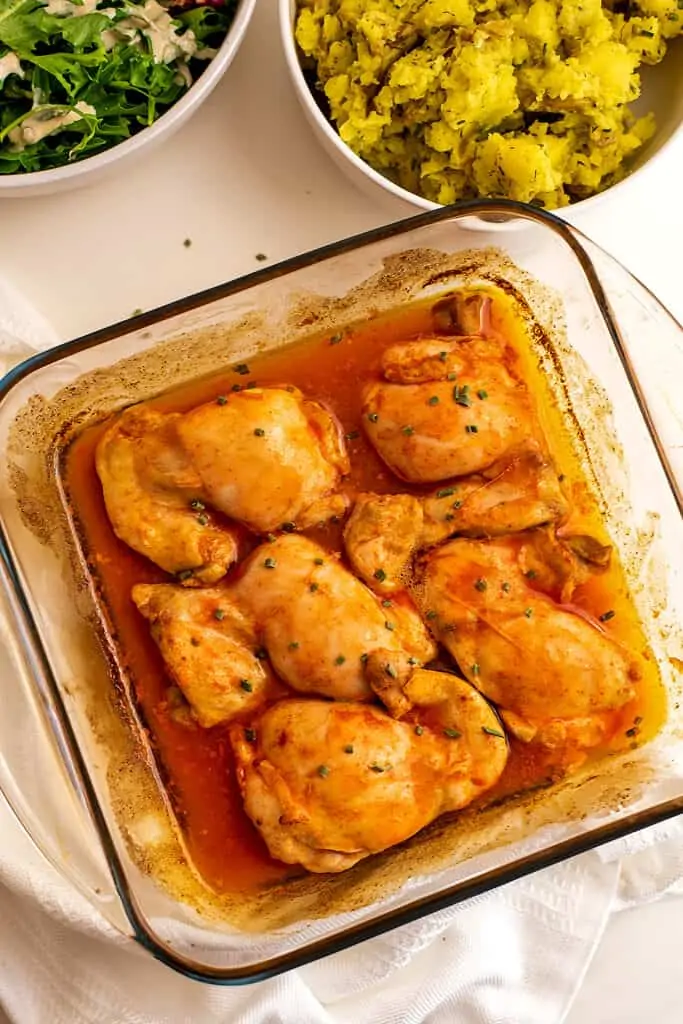 Glass casserole dish filled with baked buffalo chicken thighs.