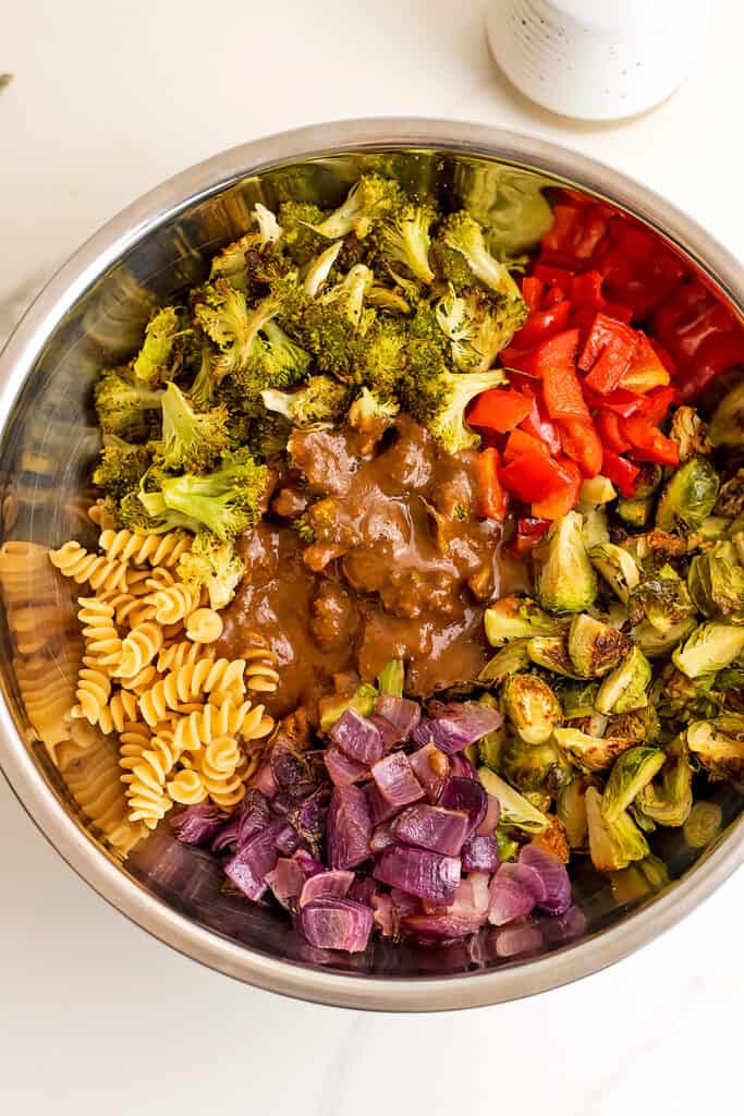 Roasted vegetable pasta salad in silver bowl before stirring.