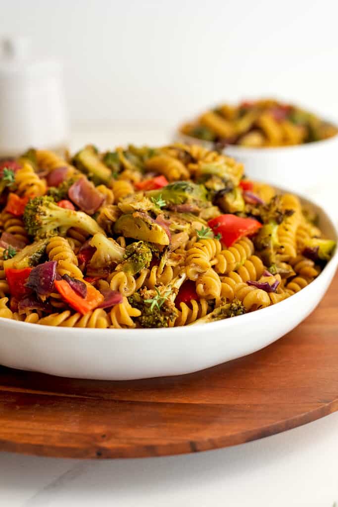 Fall pasta salad in large white bowl with smaller bowl in background.