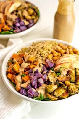 Fall quinoa salad in bowl with bottle of dressing in background.