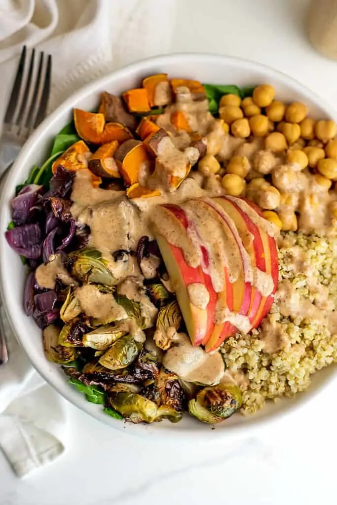 Roasted vegetable quinoa bowl with maple tahini dressing in bowl.