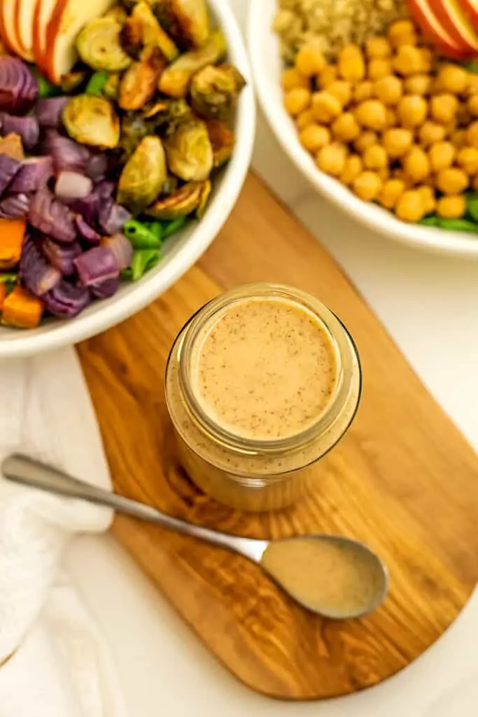Jar of maple tahini dressing with a spoon of dressing on side.