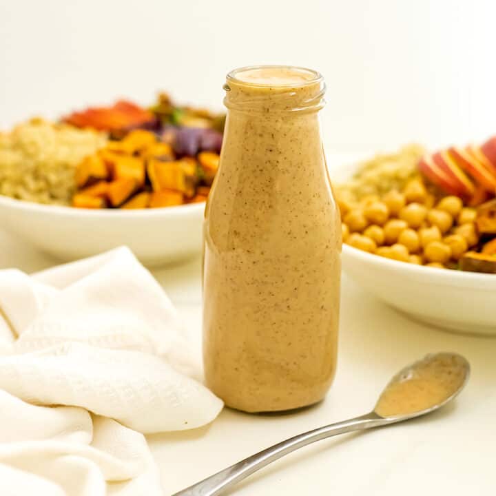 Bottle of maple tahini dressing with spoon in front of bottle.