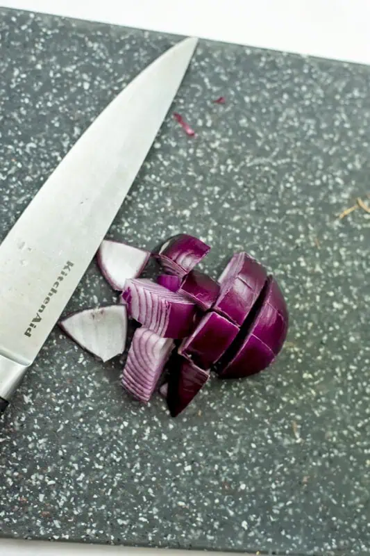 Red onion diced on a grey cutting board.
