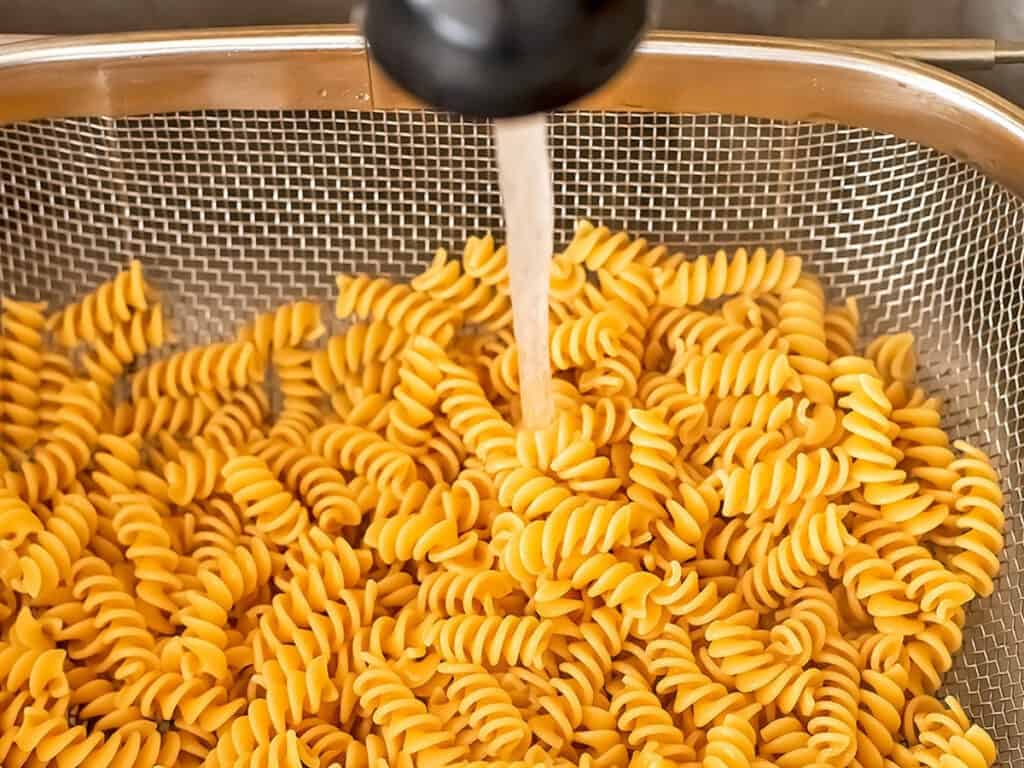 Pasta being rinsed with cold water.