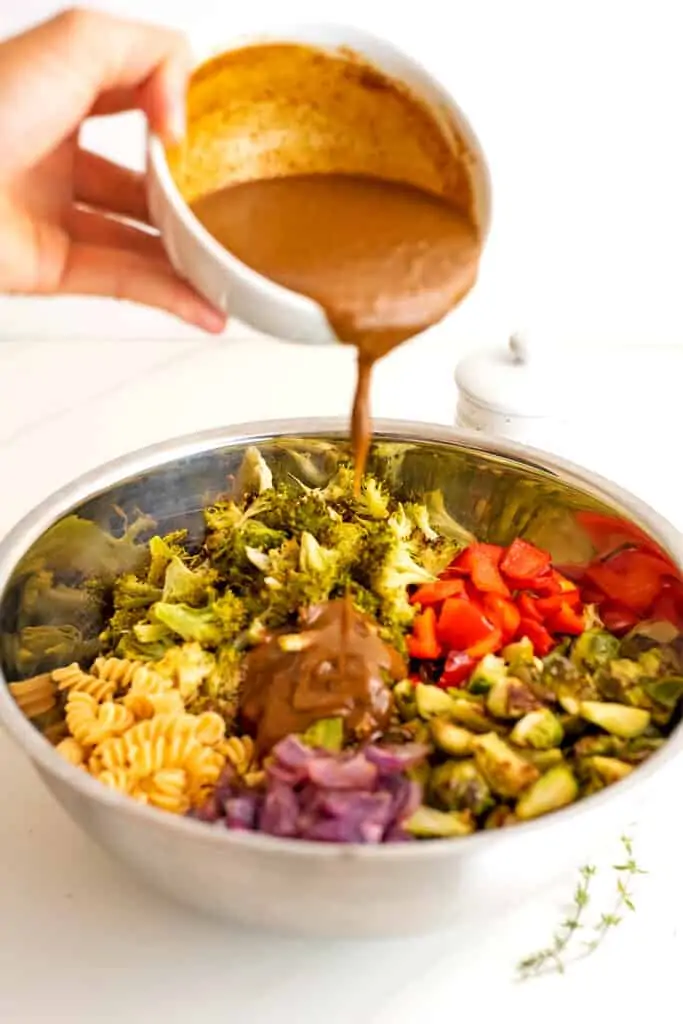 Creamy balsamic dressing being poured over the pasta salad.