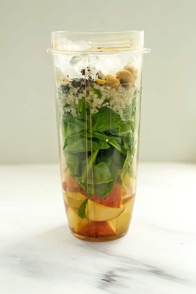 Apple banana spinach smoothie in blender cup before blending.