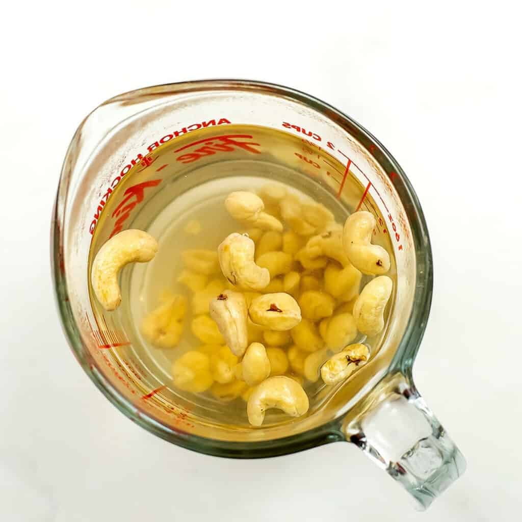 Raw cashews being soaked in hot water.