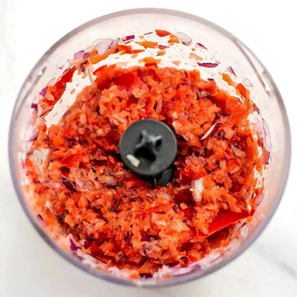 Red bell pepper and red onion in food processor.