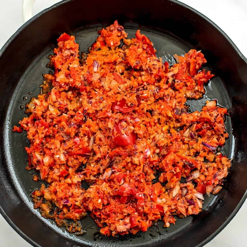 Chopped bell pepper and onion in cast iron skillet before cooking.