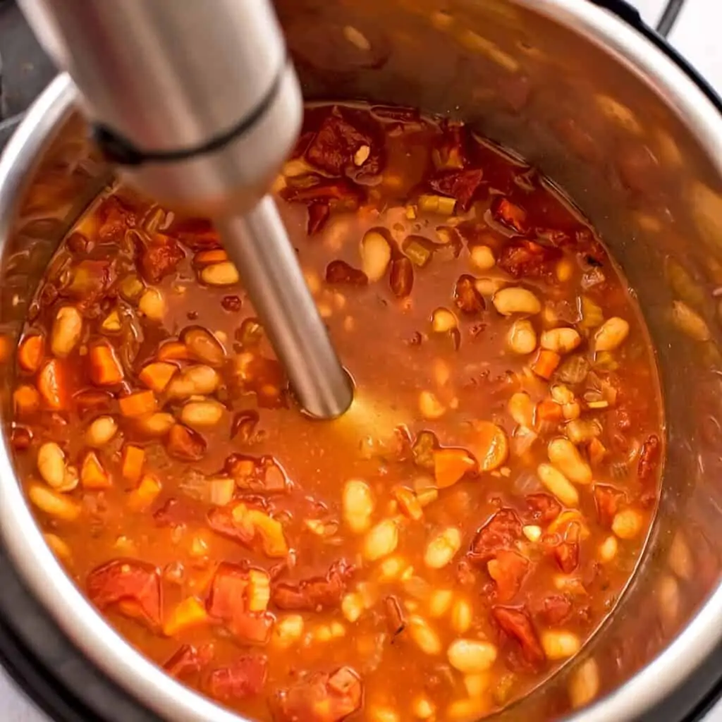 Immersion blender in instant pot blending soup.