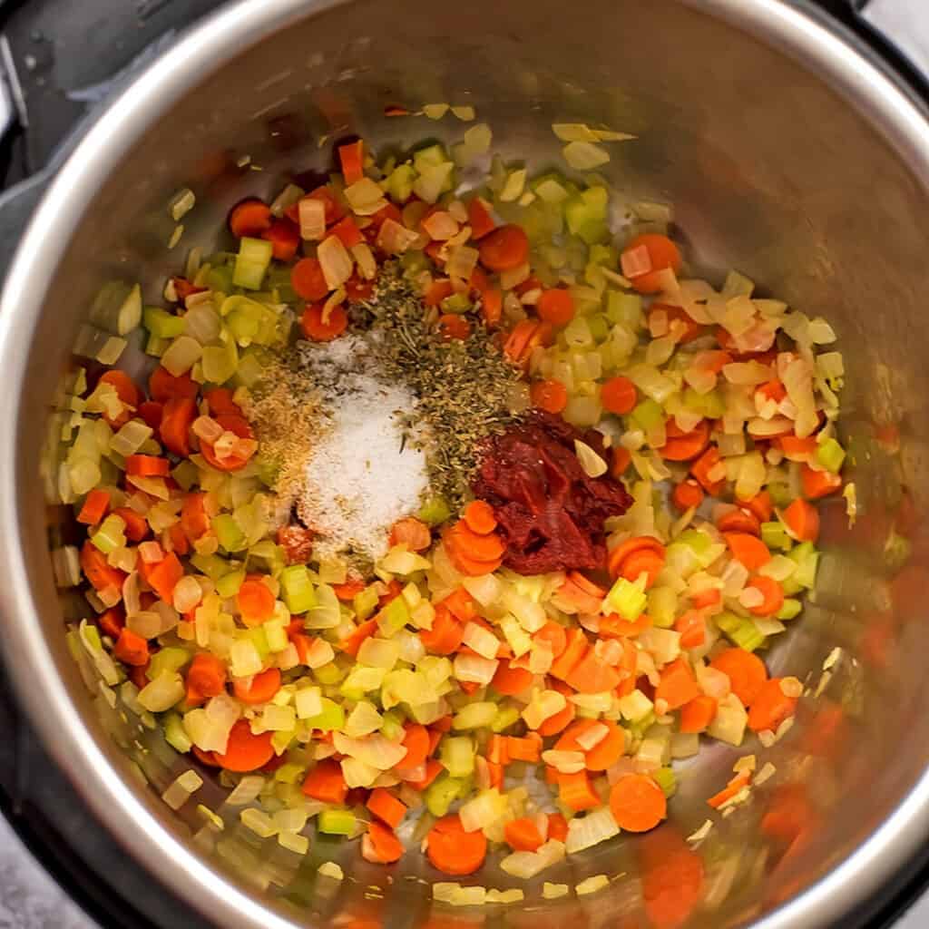Tomato paste and spices added to veggies in instant pot.