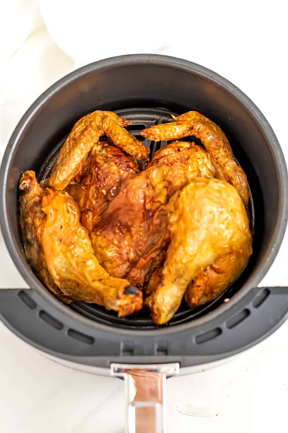 Air fryer basket with spatchcock chicken.