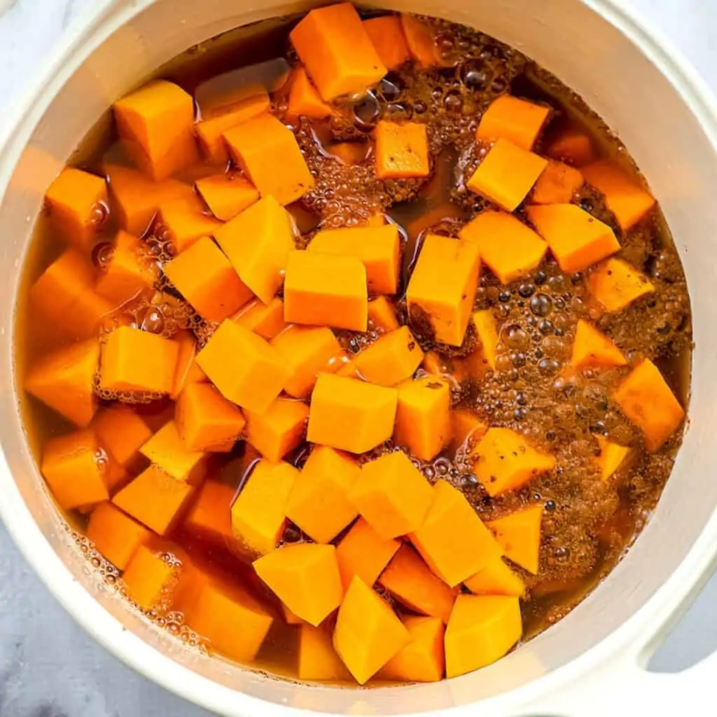 Pot filled with butternut squash, broth, cinnamon and salt.