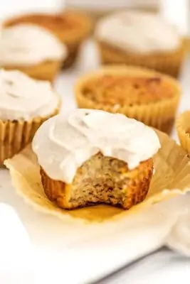 Cupcake topped with cashew frosting wiht a bite taken from the cupcake.