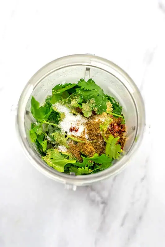 Blender cup filled with ingredients to make cilantro lime vinaigrette.