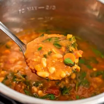 Tuscan white bean soup being ladeled out of instant pot.