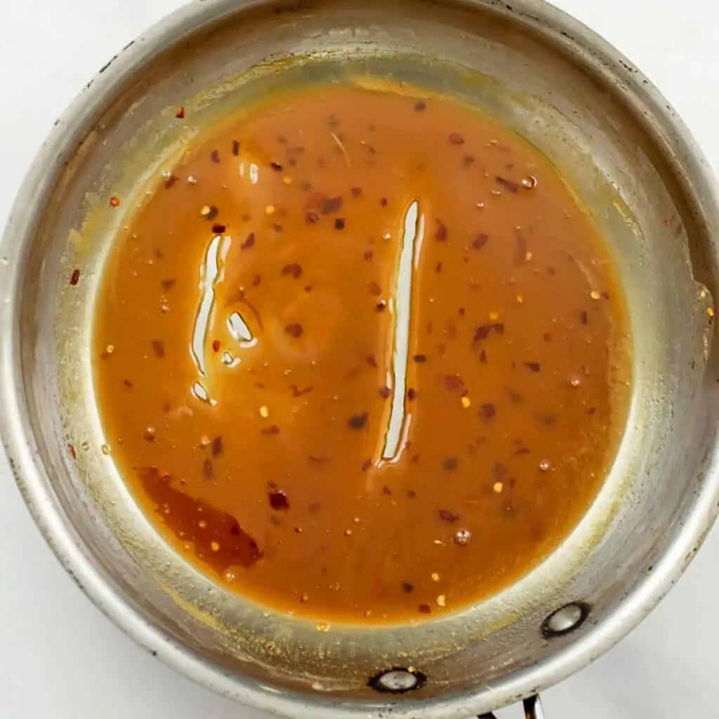 Orange sauce after cooking with line down center to show thickness of sauce.