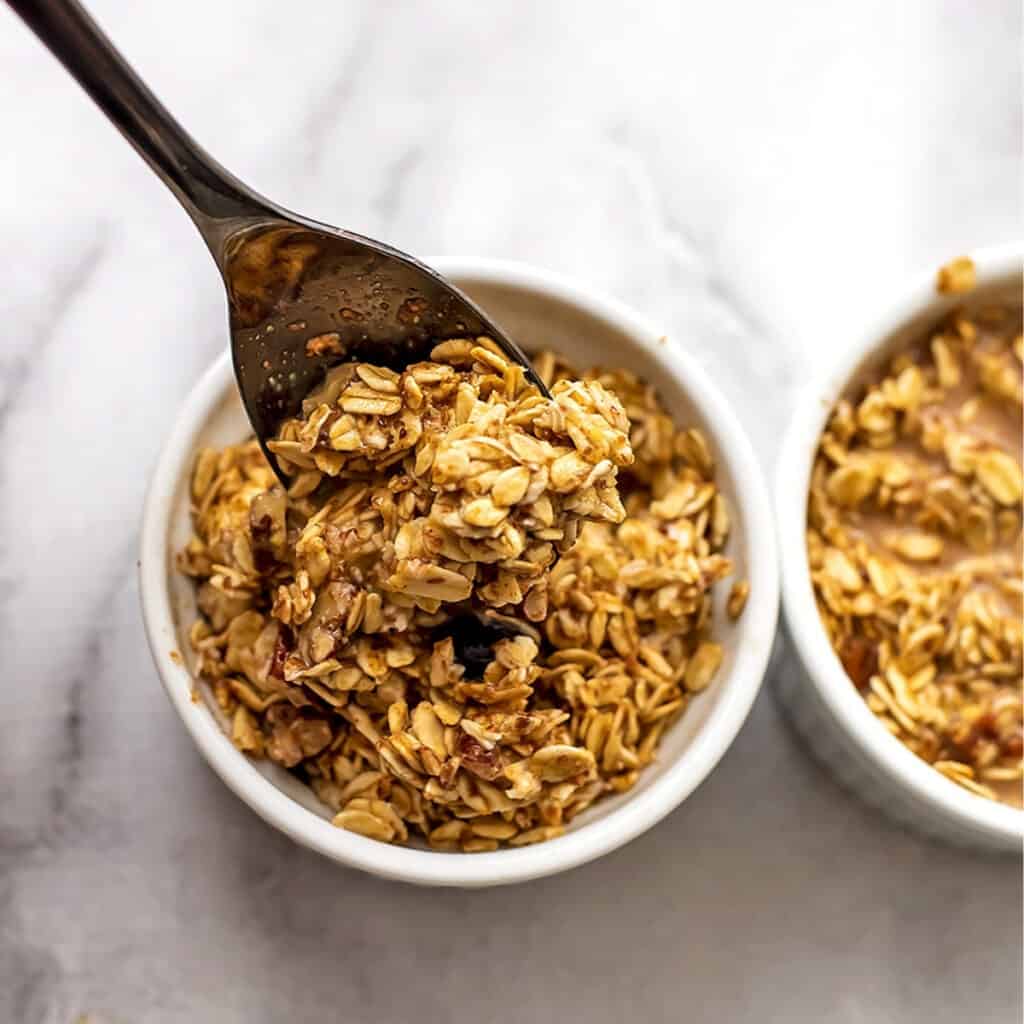 Spoon stirring oat mixture in ramekins.