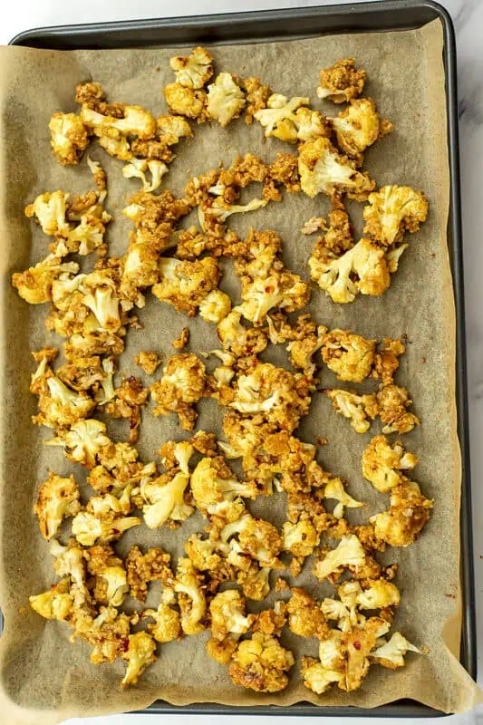 Crispy cauliflower on a baking sheet before tossing in sauce.