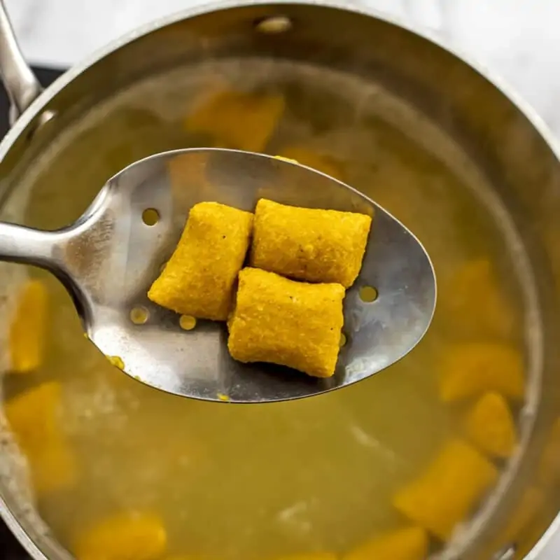 Silver slotted spoon removing gnocchi after boiling.