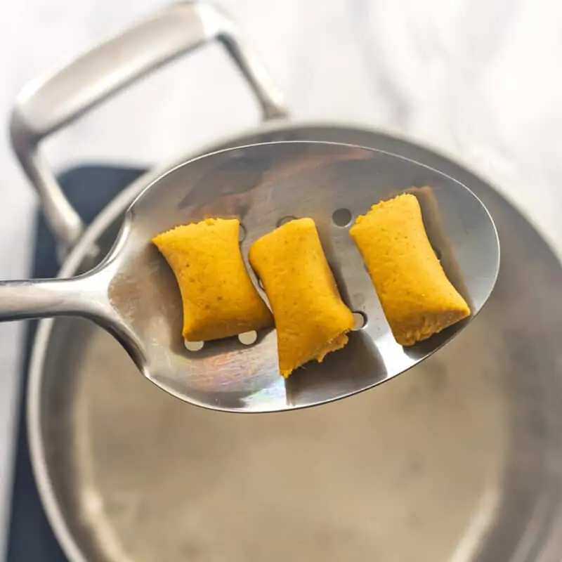 Gnocchi on slotted spoon before boiling.