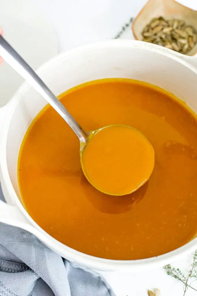 Large ladle filled with Whole30 butternut squash soup.