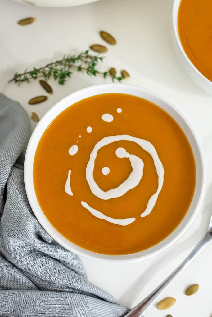 Butternut squash soup in white bowl with cashew drizzle on top. 