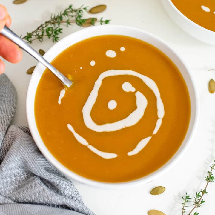 Butternut squash soup in a white bowl with spoon in bowl.