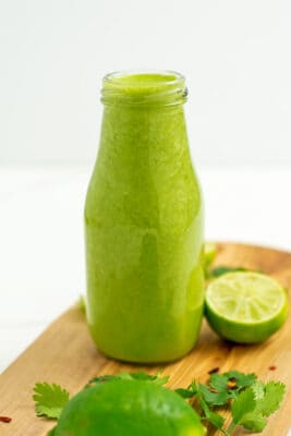 Bottle of cilantro lime vinagrette on wooden cutting board.