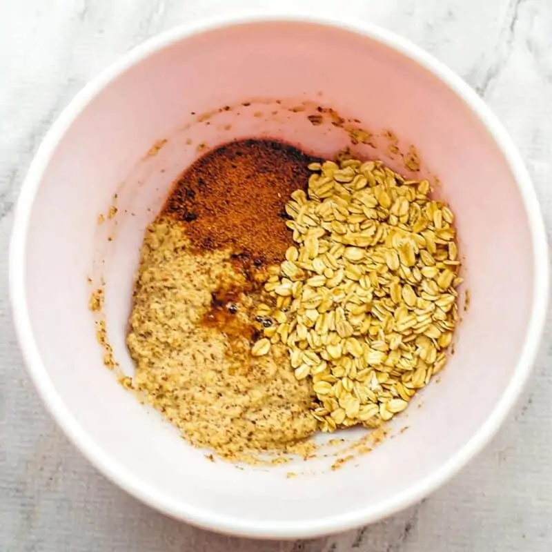 Rolled oats, coconut sugar, vanilla extract in bowl.