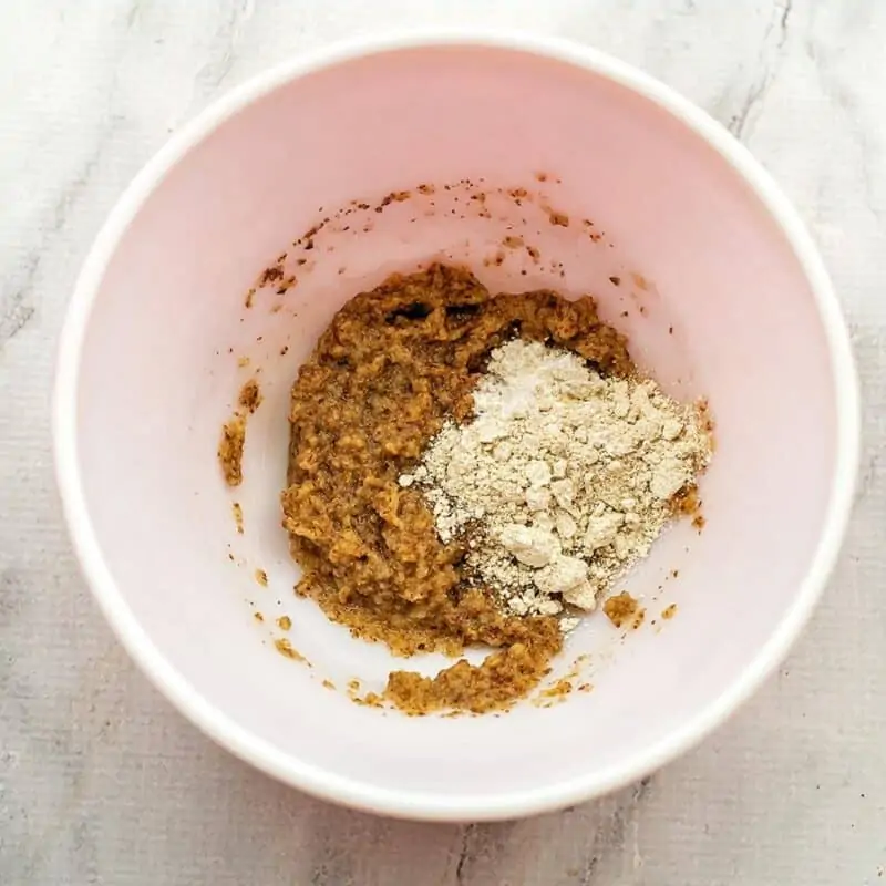 Flour and baking powder in bowl with applesauce and flax mixture.