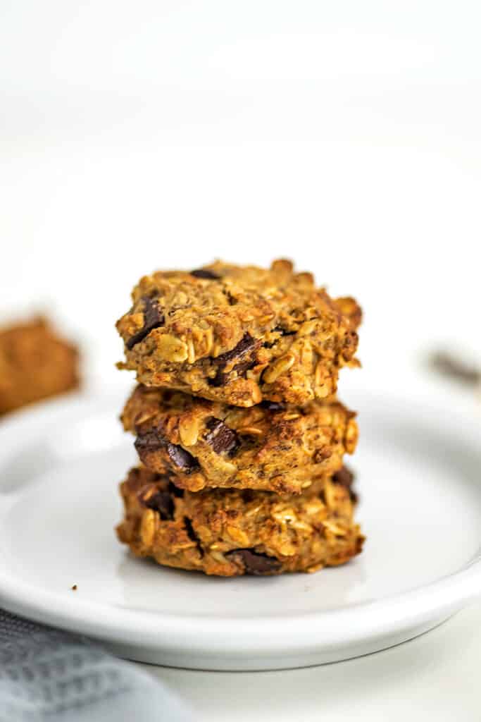Vegan chocolate chip oatmeal cookies stacked on a plate.